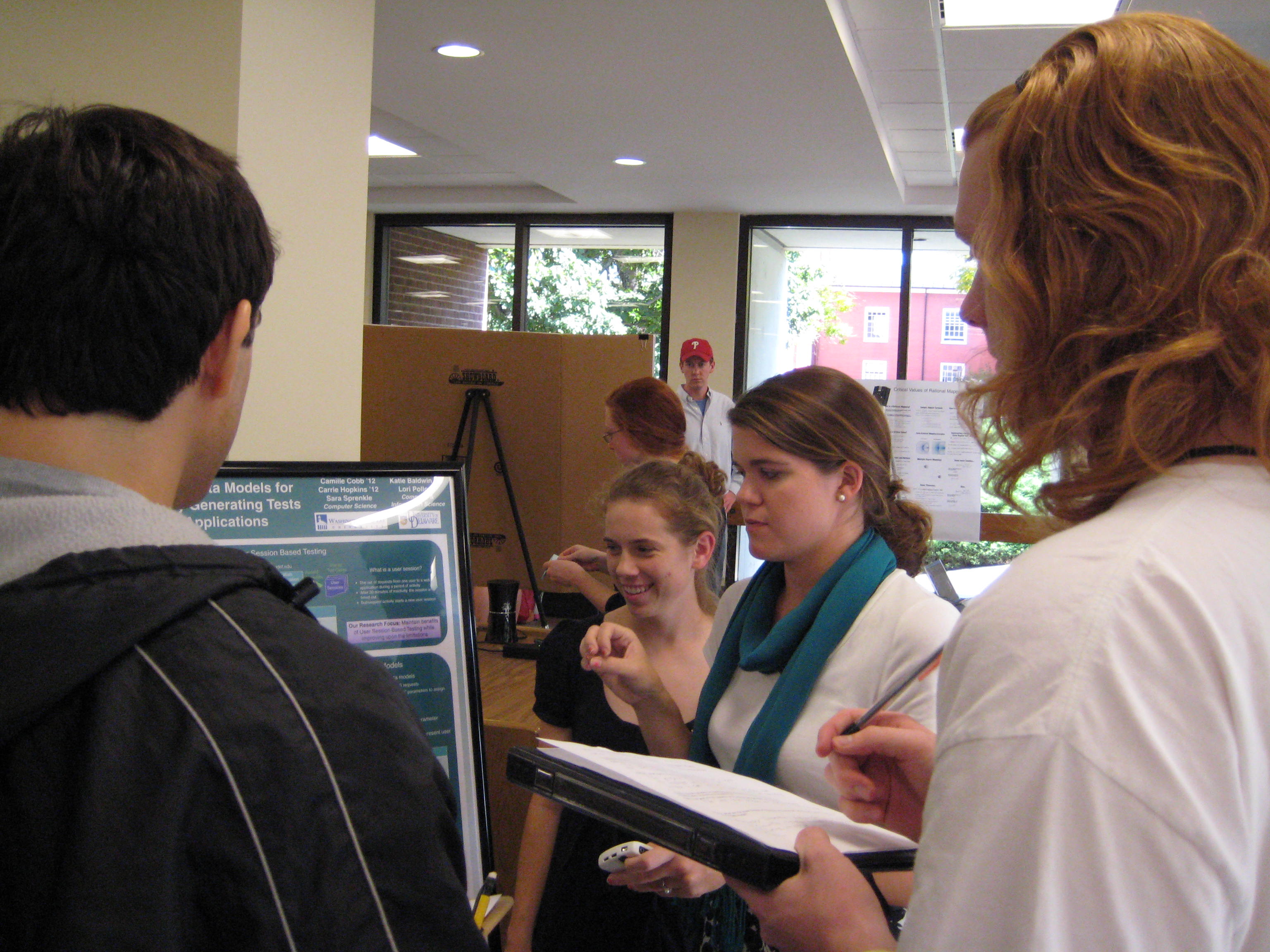 Camille and Carrie (center) present their research to computer science students, David (l) and Levi (r).